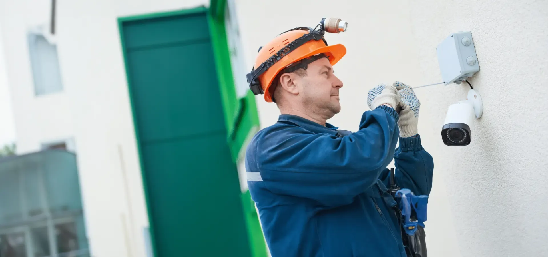 Trabajador técnico instalando cámara de videovigilancia en la pared